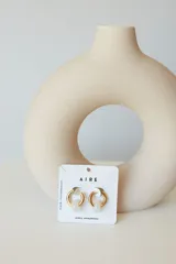 Aros dorados con dije circular de piedra natural negra.