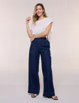 Jean de tiro alto y pierna amplia de corte wide leg, confeccionado en denim azul. Presenta cintura plana en el frente y elastizada en la espalda, bolsillos delanteros aplicados estilo parche y pespuntes a contrapunto.