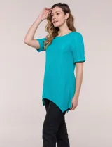 Blusa blanca de tejido de punto liviano con textura labrada en franjas verticales y caladas, de silueta evasé, con escote redondo, manga corta y ruedo asimétrico en picos.