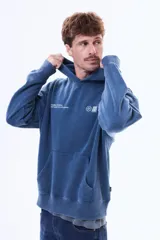 Buzo tipo canguro de felpa color azul con efecto lavado, capucha, bolsillo frontal tipo canguro y estampado gráfico pequeño en el pecho.