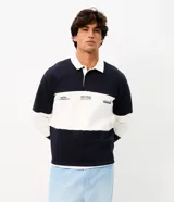 Buzo masculino confeccionado en algodón con felpa y diseño de bloques rayados en color azul marino y blanco. Presenta cuello polo, cierre frontal parcial con botones, manga larga y estampa frontal con íconos y texto.