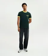 Remera de algodón color verde oscuro con cuello redondo y bordes de mangas en color amarillo. Presenta un bordado frontal con la palabra Brasil y estrellas en color amarillo.