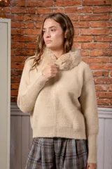 Campera de punto texturizado color beige, con cierre frontal completo y cuello de piel sintética al tono. Presenta mangas largas con puños ajustados y diseño holgado.