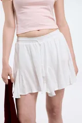 Pollera corta blanca con cintura elastizada y cordón regulable con borlas. Presenta volados en el ruedo.