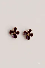 Aros tipo caravanas con diseño de flor de cuatro pétalos en color bordó con bordes dorados y centro texturizado en tono dorado.