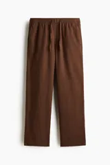 Pantalón de corte relajado color marrón, confeccionado en mezcla de lino y viscosa, con cintura elástica ajustable mediante cordón y bolsillos laterales.