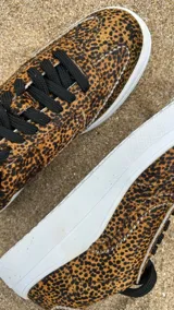 Zapatillas bajas con estampado animal print de leopardo, cordones negros y suela blanca.
