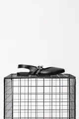 Chatas de cuero negro con punta cuadrada y talón descubierto. Presentan doble pulsera con tachas ajustables y hebilla dorada.