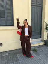 Conjunto de dos piezas compuesto por un blazer y un pantalón de corte sastrero, confeccionados en tela de algodón con estampado de rayas verticales blancas sobre fondo gris. El blazer presenta solapas clásicas y cierre frontal, mientras que el pantalón es de tiro medio y pierna recta.