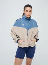 Campera cortaventos Umbro de diseño colorblock en tonos celeste, beige y azul marino, con cuello alto, cierre frontal y bolsillos laterales.