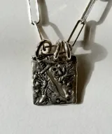 Collar de plata con cadena de eslabones y un dije rectangular texturizado con diseño artesanal.