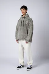 Buzo canguro oversize de algodón friza con efecto de teñido artesanal desgastado. Presenta capucha con cordones negros, bolsillo frontal tipo canguro y estampa pequeña de Popeye en el pecho.