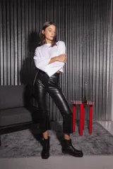 Pantalón de tela engomada color negro, con corte capri semi oxford, tiro medio-alto, cierre frontal con botón metálico y bolsillos traseros.