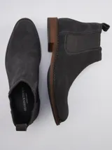 Bota Chelsea de gamuza gris con elásticos laterales, suela de goma marrón y tirador trasero.