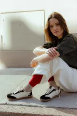 Zapatillas urbanas de cuero color beige y blanco con detalles en animal print en el talón y cordones marrones.