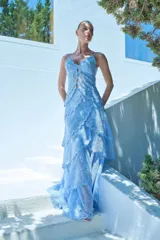 Vestido largo celeste de encaje con diseño de volados escalonados en la falda, tirantes finos y escote pronunciado con detalles de aberturas frontales.