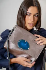 Sobre de cuero color suela con solapa frontal decorada con una piedra de ágata natural enmarcada en metal. Incluye correa larga ajustable y extraíble para usar como bandolera.