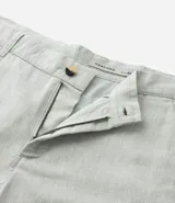 Bermuda de hombre en lino color gris claro, de corte recto, con textura discreta, bolsillos laterales y cierre frontal con botón y cremallera.