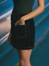 Minifalda de pana color azul oscuro con costuras en contraste color ocre. Presenta diseño de cinco bolsillos, cierre frontal con botones y trabillas para cinturón.