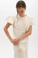 Blusa negra de lino con bordado en relieve de formas orgánicas, mangas cortas con volados y terminaciones desflecadas.