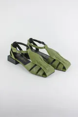 Sandalias de cuero color verde militar con diseño de tiras cruzadas, punta cuadrada, taco cuadrado bajo de color negro y tira ajustable con hebilla en el tobillo.
