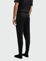 Pantalones deportivos negros de corte ajustado con una franja dorada en el lateral.