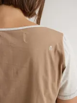 Remera gris de algodón y spandex, de manga corta y cuello redondo. Presenta líneas verticales en blanco y negro. Corte recto.