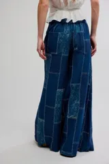 Pantalón flare de tiro alto, color azul, con diseño de patchwork y costuras visibles en contraste. Presenta perneras anchas de corte fluido.