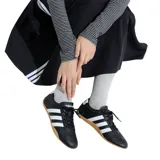 Championes Adidas de estilo tenis, color negro con tres franjas laterales blancas y talón blanco con logo. Suela de goma color caramelo.