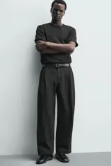 Pantalón chino de corte wide fit confeccionado en tejido de algodón. Presenta pliegues frontales, bolsillos laterales y bolsillos traseros de vivo, con cierre frontal de cremallera y botón.
