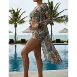 Conjunto de traje de baño de tres piezas con estampado de hojas tropicales en tonos blanco y negro. Incluye un top tipo tankini con cordón ajustable en el centro, un short de tiro alto y una camisa abierta de manga larga tipo salida de baño.