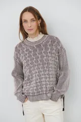 Buzo de tejido de punto con diseño reversible, cuello redondo y mangas largas. Presenta un patrón de textura trenzada en un lado y rayas verticales en el otro, con terminaciones acanaladas en puños y ruedo.