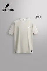 Camiseta de entrenamiento regular fit color beige, confeccionada en combinación de tejidos técnicos ligeros y elásticos con tecnología Quick Dry nivel 2. Presenta cuello redondo, manga corta, acabados con costuras planas y termofijadas, y detalle de logo estampado en el bajo.