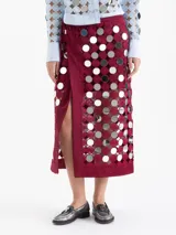 Pollera cruzada color bordó, confeccionada en guipur con recortes circulares y espejos bordados. Posee un forro interno al tono y acceso mediante botón de pasta.