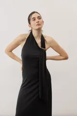 Vestido largo negro de corte al cuerpo con cuello halter y detalle de hebilla metálica dorada en el hombro con tira drapeada.