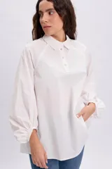 Camisa blanca de manga larga abullonada estilo globo, con cuello camisero, cierre frontal parcial de botones y diseño holgado.