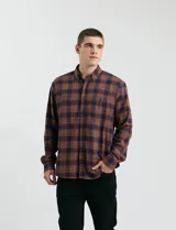 Camisa de franela a cuadros con cuello button-down, manga larga y botones de madera. Presenta dos bolsillos tipo parche en el frente con cierre de botón.