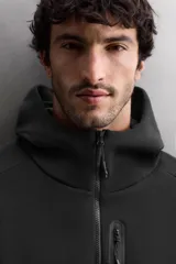 Sudadera con capucha de entrenamiento, confeccionada en tejido técnico de algodón con efecto neopreno. Presenta cierre frontal de cremallera, cuello subido, bolsillos laterales y un bolsillo en el pecho, todos con cierre de cremallera y acabado termofijado.