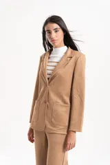 Blazer de gamuza con solapas clásicas, bolsillos frontales y corte sastrero.