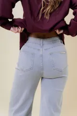 Pantalón de jean estilo wide leg, color celeste claro, con tiro medio, cinco bolsillos y cierre frontal con botón y cremallera.