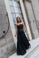 Pollera larga de corte amplio y fluido, confeccionada en tela oscura con costuras verticales visibles.