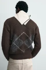 Jersey de punto marrón oscuro con diseño jacquard de rombos en gris y blanco, cuello redondo y manga larga.