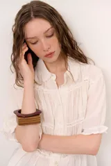 Camisa beige de manga corta con cuello camisero, detalles de encaje y cierre frontal con botones.