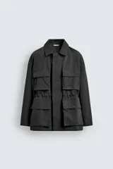 Cazadora relaxed fit de hombre, confeccionada en tejido técnico con algodón de color negro. Cuenta con cuello camisero, manga larga y bolsillos frontales de plastrón con solapa. Presenta cintura ajustable con cordón interior y cierre frontal con cremallera oculta por solapa con botones a presión.