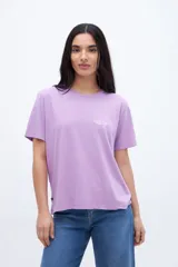 Remera de algodón color lila con cuello redondo y manga corta. Presenta un pequeño bordado en el pecho con texto en color blanco.