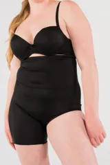 Calza modeladora negra reforzada en zona abdominal, tiro alto y corte a media pierna en la pierna derecha.