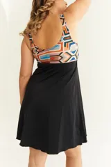 Malla entera con short y vestido negro, con corpiño estampado con motivos geométricos en tonos naranja, celeste y marrón. Presenta un nudo en el centro del escote para regular la profundidad.