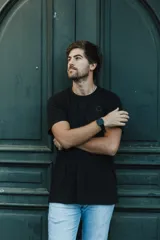 Remera negra de manga corta con cuello redondo y un pequeño logo circular en el pecho.