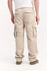 Pantalón cargo de fit baggy color beige, con piernas amplias, bolsillos laterales con tapa y costuras decorativas.