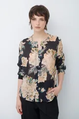Camisa de manga larga con estampado floral sobre base oscura, cuello redondo con pequeña abertura en V y cierre frontal con botones.